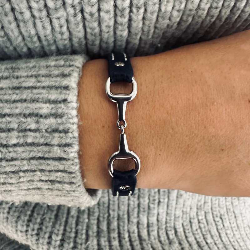 A close-up of a wrist wearing the Fano Leather Bracelet with Rhinestones, shown against the sleeve of a light grey knitted jumper.
