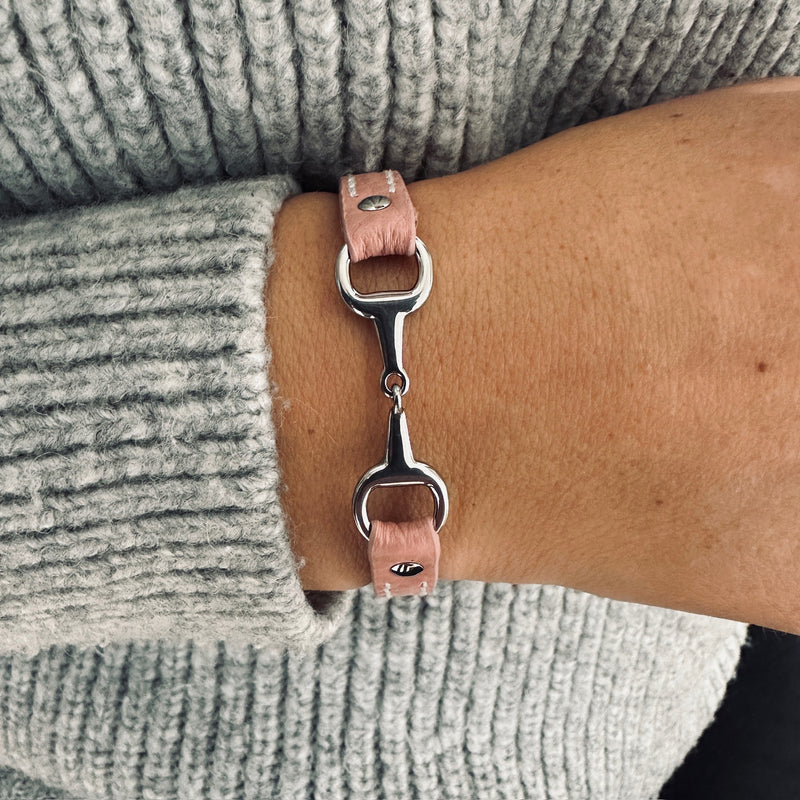 A person wearing a Fano Leather Bracelet with Rhinestones on their wrist, paired with a chunky light grey knit jumper.