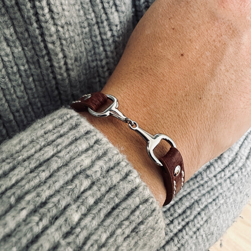 A close-up of a wrist wearing the Fano Leather Bracelet with Rhinestones, paired with a chunky light grey knitted jumper.