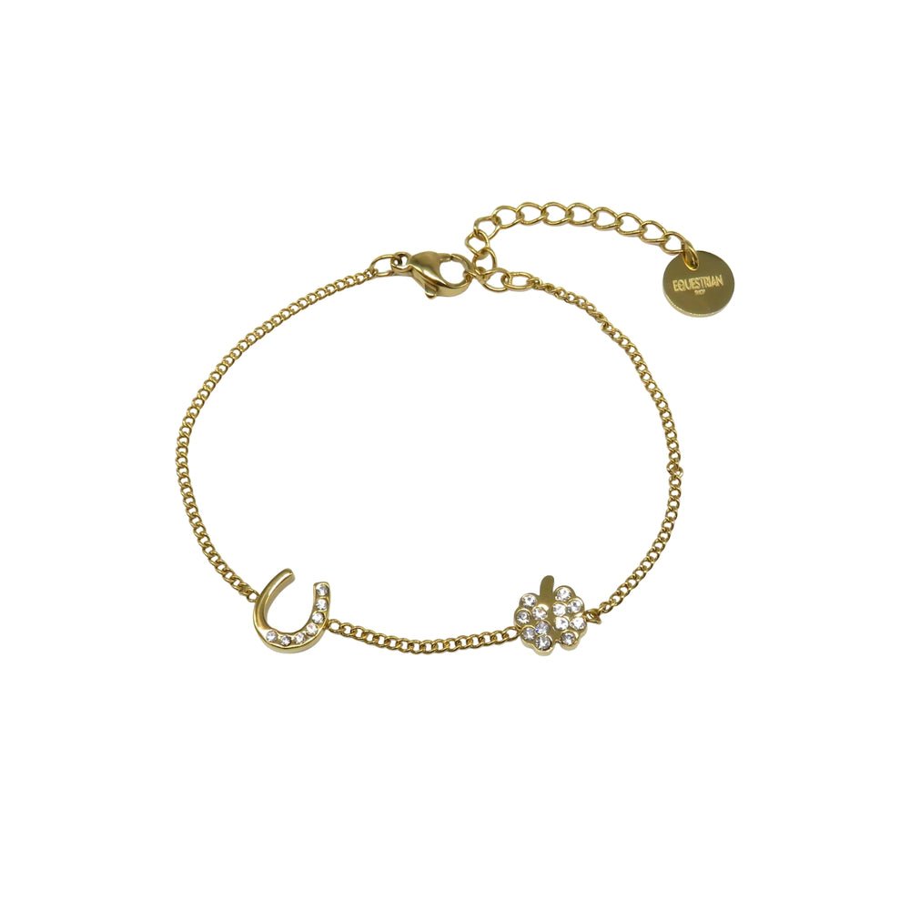 A delicate gold chain bracelet with a crystal-studded horseshoe charm, a sparkling four-leaf clover charm, and an adjustable clasp with a round tag engraved EQUESTRIAN.