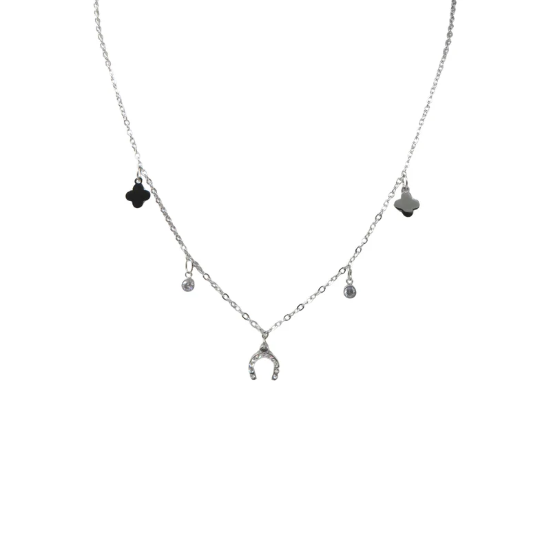 The Ziggy Necklace is a delicate silver chain adorned with two black four-leaf clover charms, a central horseshoe charm, and two round gemstone accents.