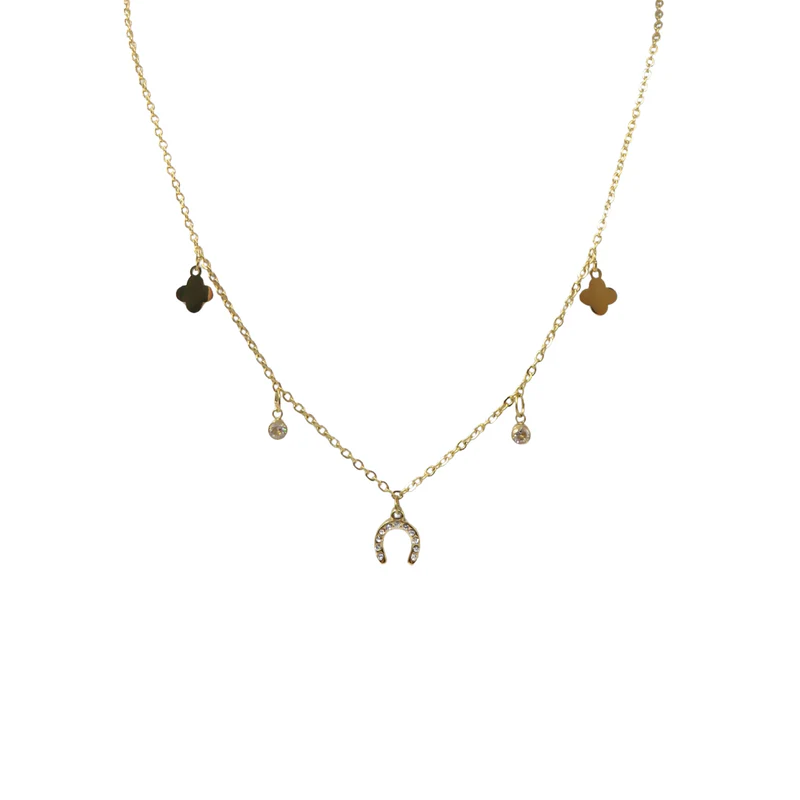 The Ziggy Necklace showcases a gold chain with charms—a central horseshoe, two jewelled pendants, and two clover accents—spaced delicately along its length and displayed against a white background.