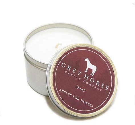 A white candle in a round metal tin with a maroon label reading "Grey Horse Candle Tins, Apples for Horses" stands out as a classic Grey Horse product.